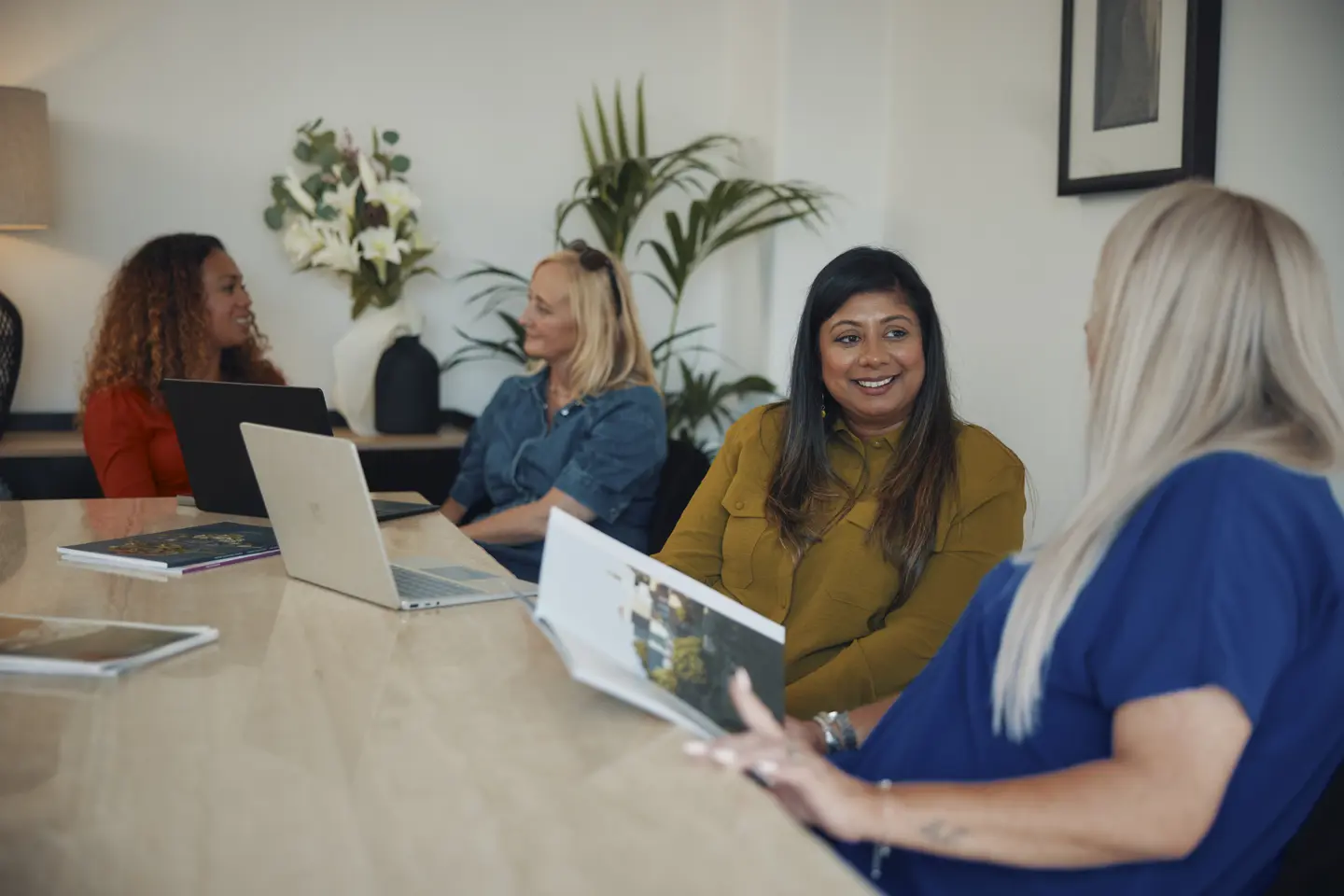 Blonde lady sat at kitchen table working on a laptop