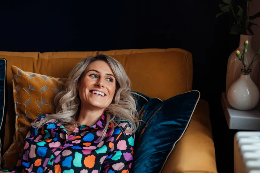 blonde woman relaxing on a sofa, smiling off into the distance