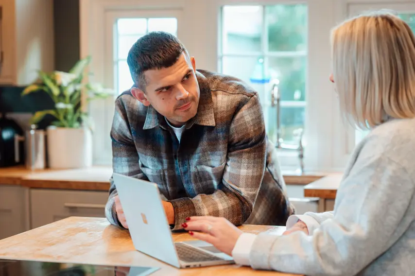 Two Travel Counsellors talking to each other at a kitchen table 