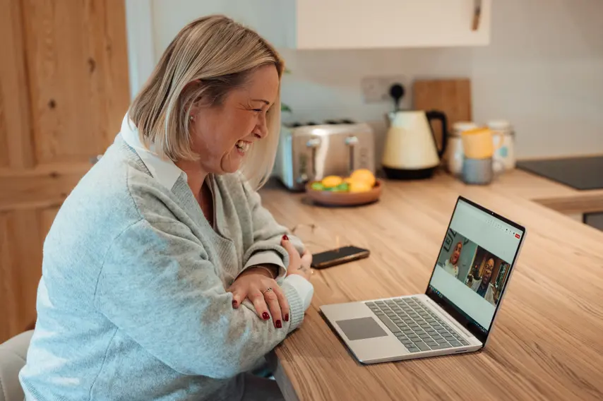 Female Travel Counsellors sat at breakfast bar on laptop on a Teams Meeting