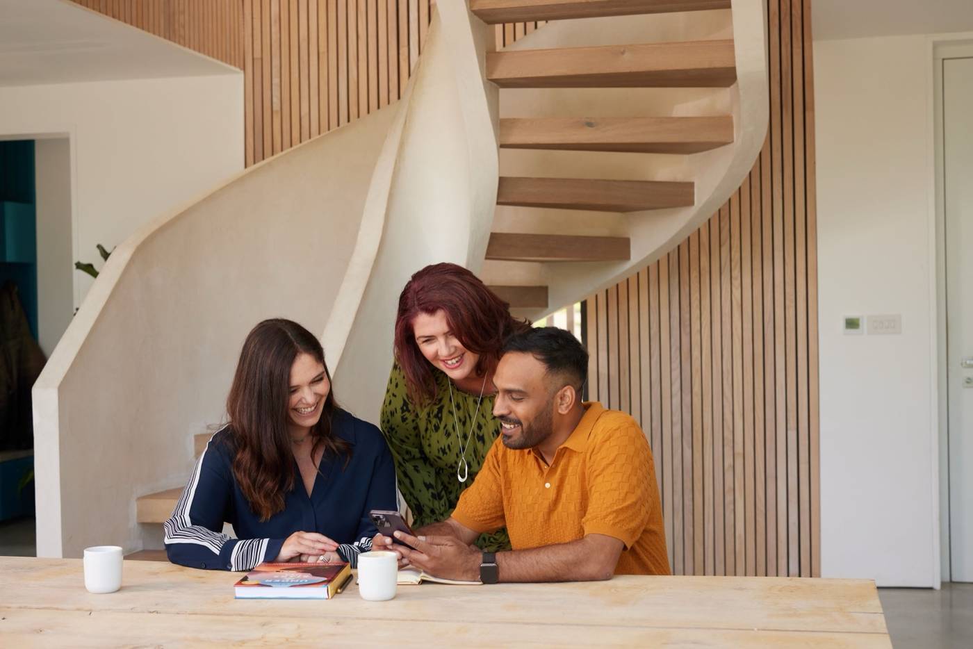Three Travel Counsellors sat together looking at something on a mobile phone